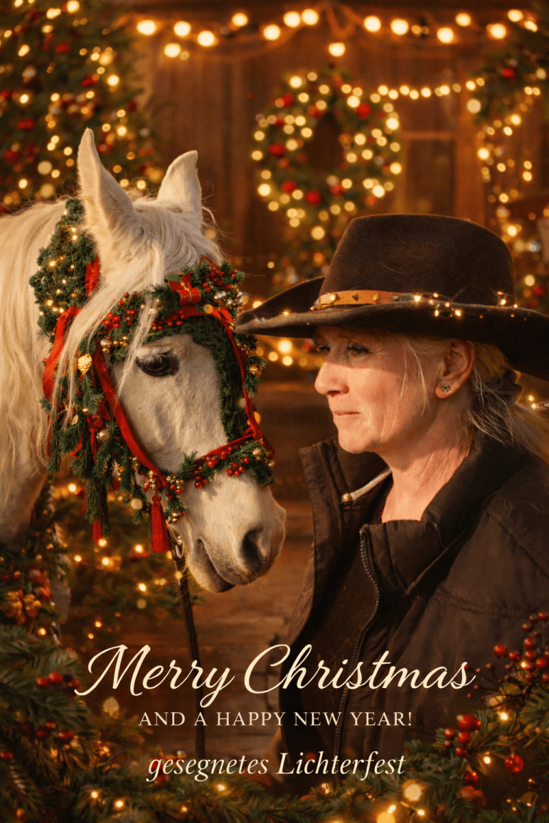 Weißes Pferd mit weihnachtlichem Tannenschmuck steht ruhig neben einer Frau mit Cowboyhut in warmem Lichterglanz.